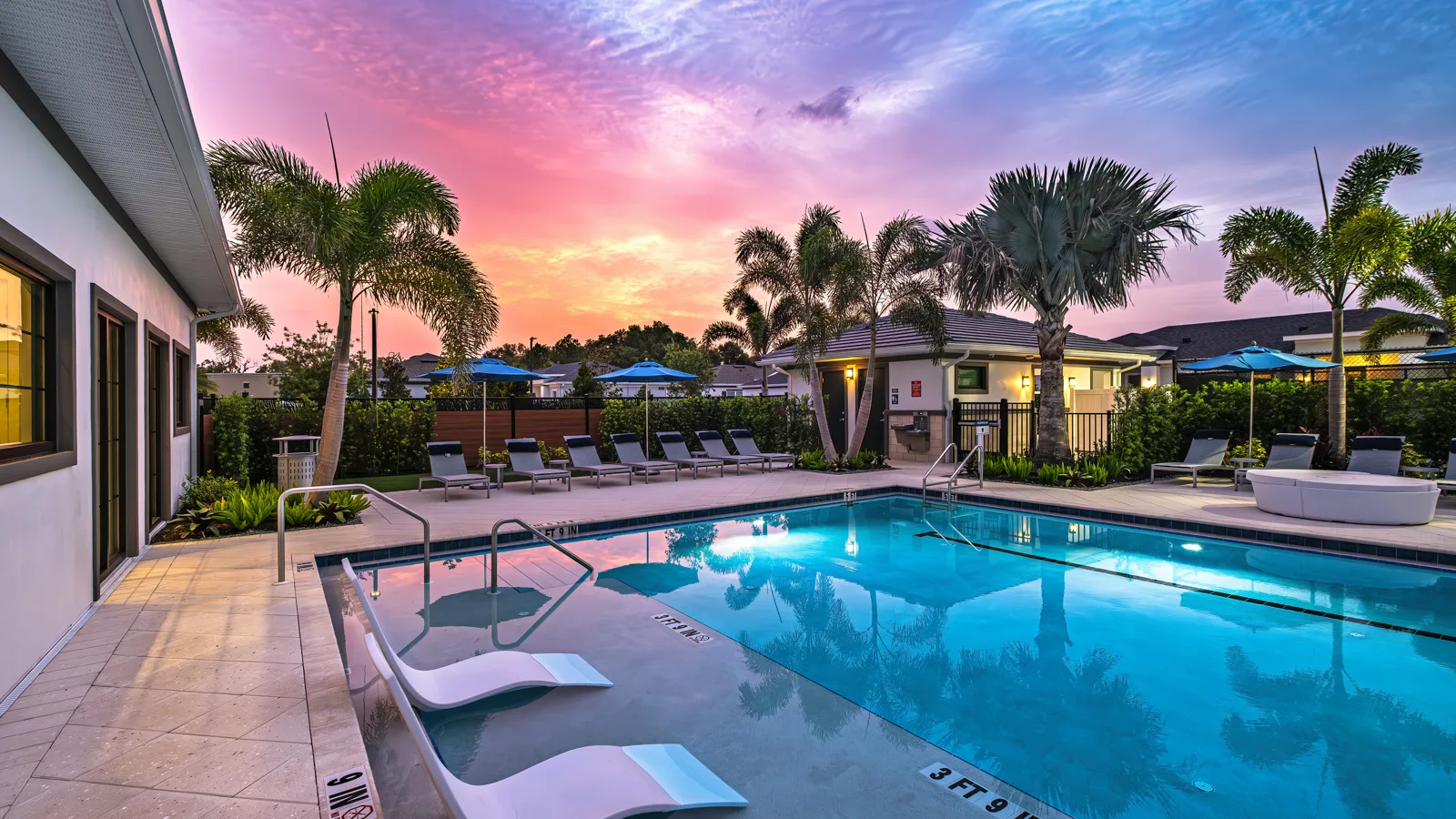 Beautiful twilight photo of the brand-new sparkling resort style pool at Yardly Artisan Lakes in Palmetto, FL. This beautiful new home rental community also features a pickleball court, clubhouse, dog park and onsite gym.