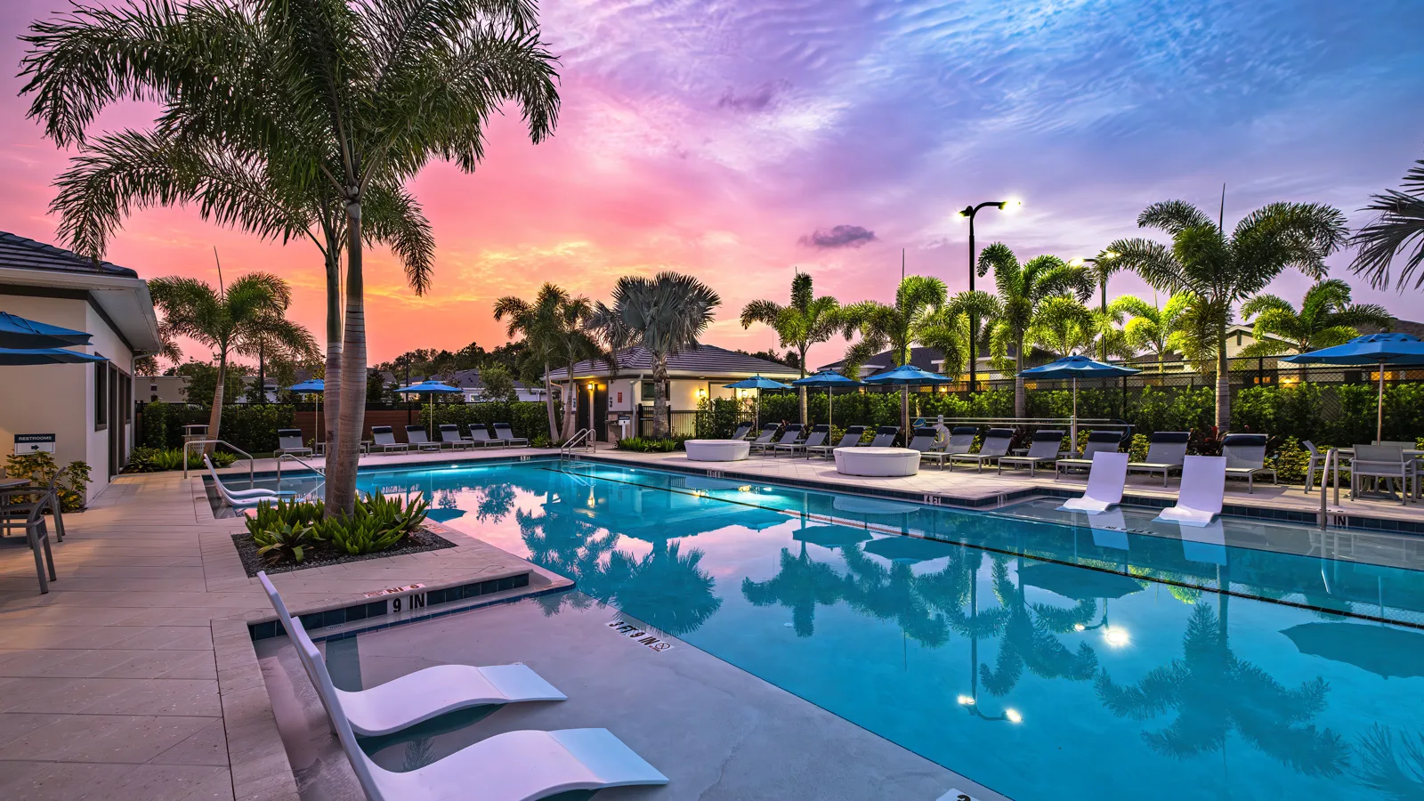 Beautiful twilight photo of the brand-new sparkling resort style pool at Yardly Artisan Lakes in Palmetto, FL. This beautiful new home rental community also features a pickleball court, clubhouse, dog park and onsite gym.